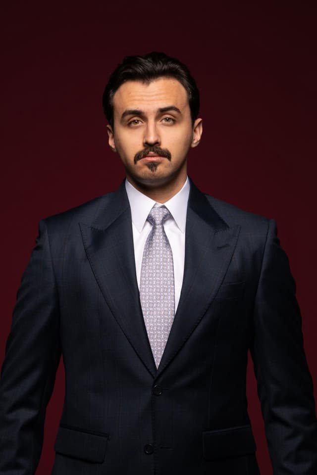 Close-up of a smiling woman touching her cheek with her hand wearing a gray ring.